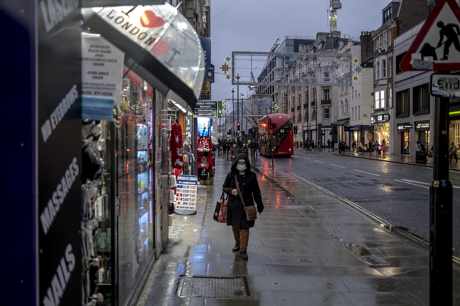 NUEVAS MEDIDAS. Una mujer camina por una calle húmeda por la lluvia en Oxford el primer día de restricciones de nivel 3 en Londres, el 16 de diciembre de 2020. 