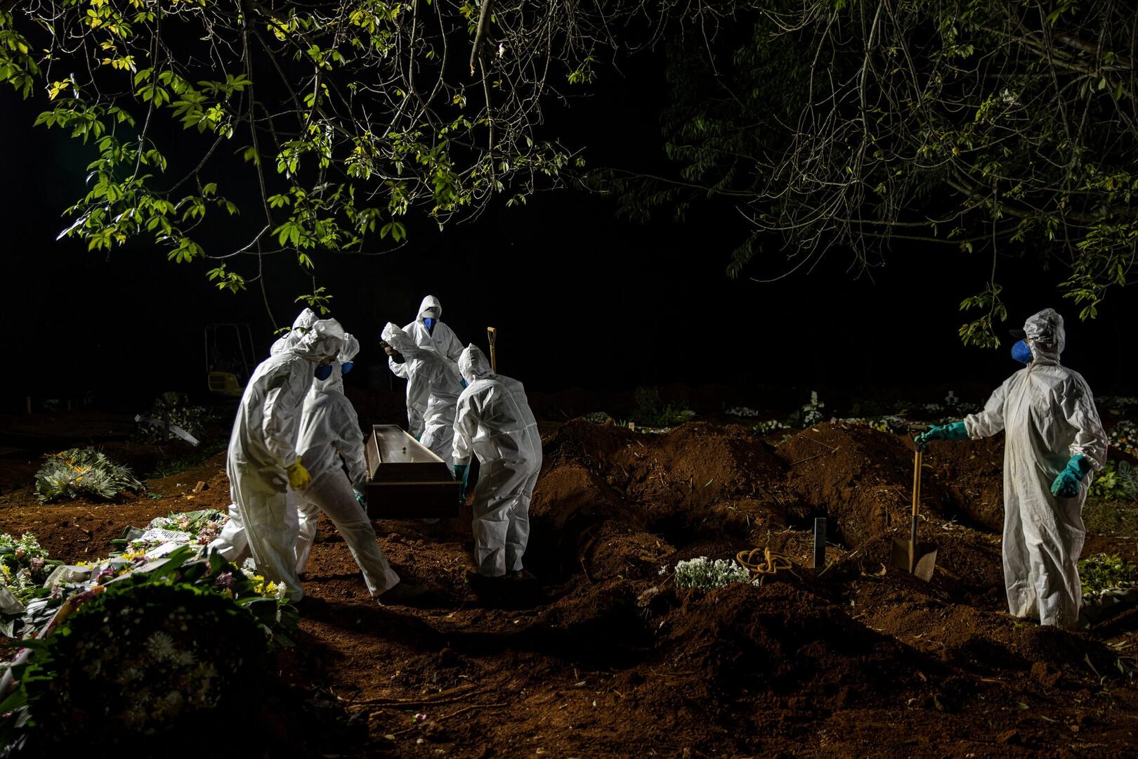 BRASIL. Trabajadores del cementerio de Vila Formosa en São Paulo llevan el ataúd de una persona que falleció por Covid-19.