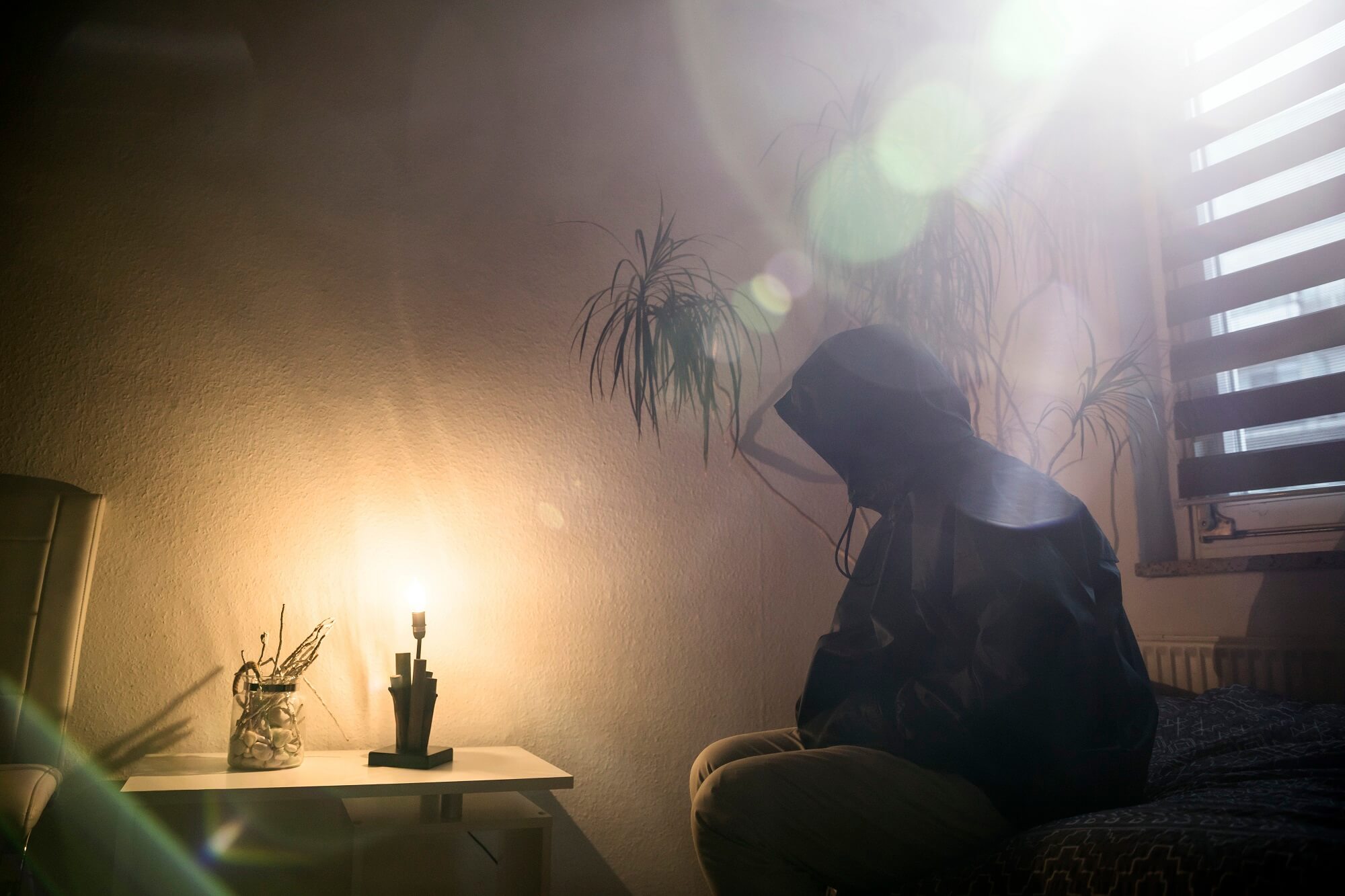 Persona inclinada en posición de rezo dentro de una habitación en la oscuridad.