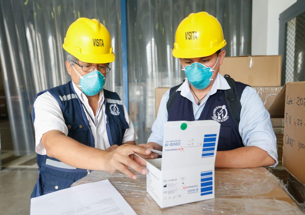 Fotografía de trabajadores del Instituto Nacional de Salud inspeccionando un cargamento de pruebas rápidas.