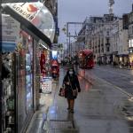 NUEVAS MEDIDAS. Una mujer camina por una calle húmeda por la lluvia en Oxford el primer día de restricciones de nivel 3 en Londres, el 16 de diciembre de 2020. 