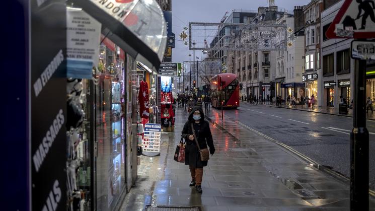 NUEVAS MEDIDAS. Una mujer camina por una calle húmeda por la lluvia en Oxford el primer día de restricciones de nivel 3 en Londres, el 16 de diciembre de 2020. 