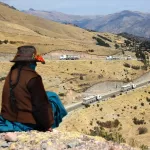 IMPACTOS. Una mujer quechua, en Challhuahuacho (Apurímac), observa la fila de camiones de Las Bambas. 