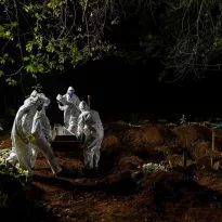 BRASIL. Trabajadores del cementerio de Vila Formosa en São Paulo llevan el ataúd de una persona que falleció por Covid-19.